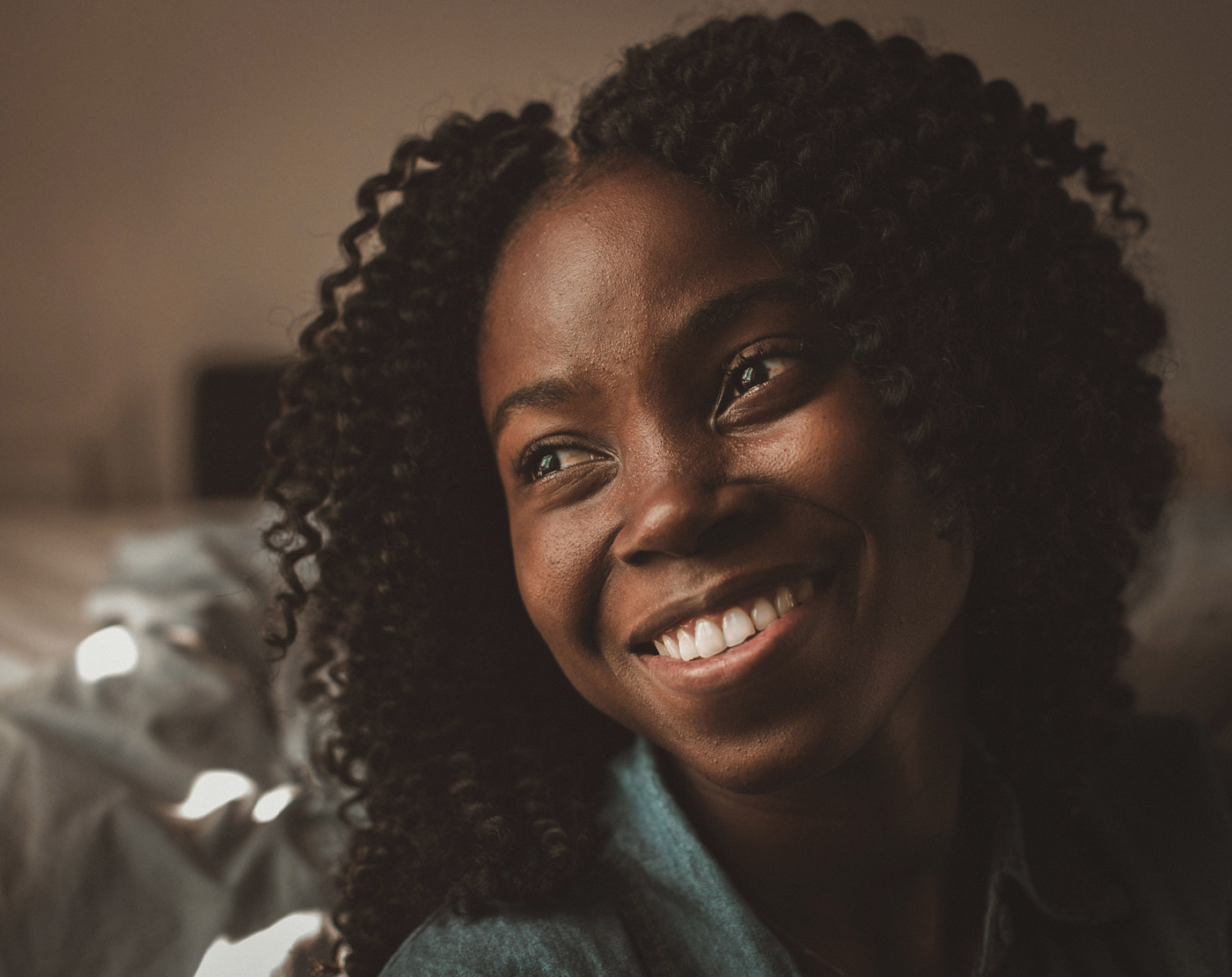 A relaxed and happy African American woman smiles and looks just beyond the camera.